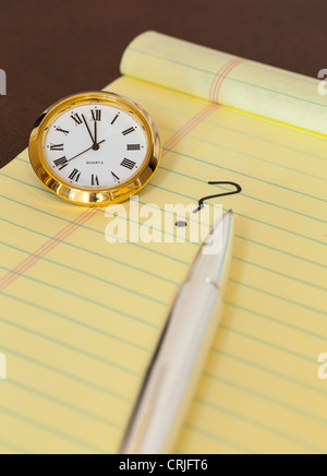 Konzept für dringende Entscheidungen mit Uhr auf Papier und Fragezeichen auf pad Stockfoto