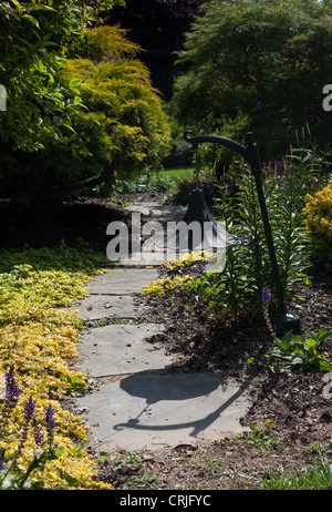 Pflasterweg führt auf gekrümmten Weise durch einen englischen Stil Strauch Garten Stockfoto