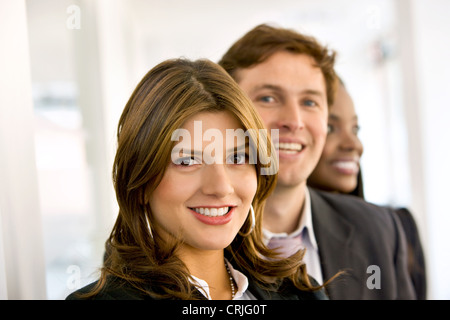 drei junge Geschäftsleute stehen hinter einander mit einem optimistischen Lächeln Stockfoto