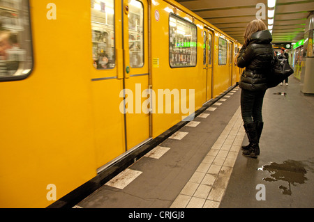 Berlin, Deutschland. U-Bahn (Untergrundbahn). Frau wartet auf der Plattform, dem Zug ankommen, Pfützen Stockfoto