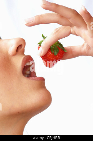 Nahaufnahme einer Frau setzen eine Erdbeere in den Mund Stockfoto