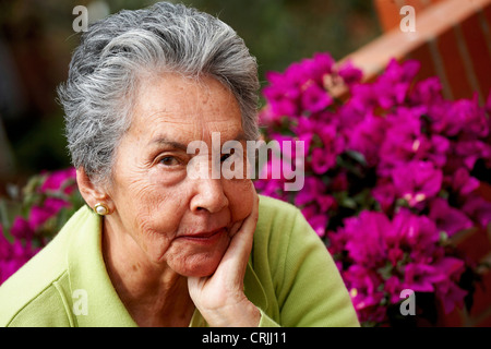 schöne ältere Frau Porträt vor lila Blumen Stockfoto