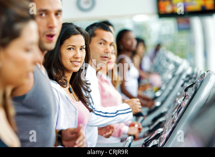 schöne Frau im Fitness-Studio Cardio-Training mit einer Gruppe von Menschen um sie herum zu tun Stockfoto