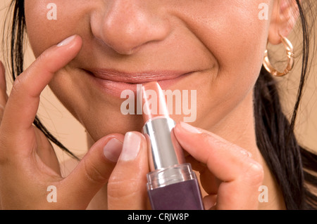 Brünette junge Frau, die immer mit Lippenstift, die an durch eine Kosmetikerin Stockfoto