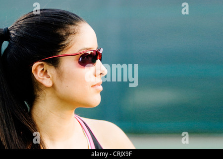 Junge lateinamerikanische Frau in Sonnenbrille mit Blick auf Gegner. Stockfoto