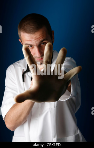 Eine junge männliche Krankenschwester erreichen, um zu zeigen, dass er Schutzhandschuhe tragen. Stockfoto