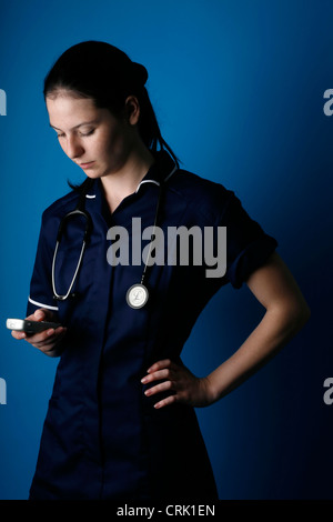 Eine junge Krankenschwester eine SMS von ihrem Mobiltelefon. Stockfoto