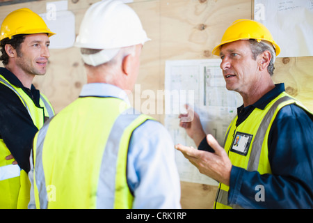 Arbeitnehmer, die Baupläne vor Ort lesen Stockfoto