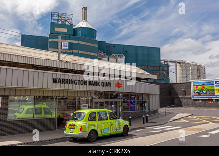 Bahnhof Warrington Bank Quay mit Unilever Fabrik hinter. Stockfoto