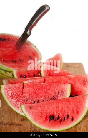 frische reife Wassermelone in Scheiben geschnitten auf einem Holztisch mit Messer auf weißem Hintergrund Stockfoto