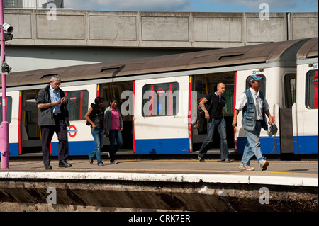 Passagiere, die zu Fuß entlang einer Plattform neben einer Londoner U-Bahn Zug am Bahnhof, England. Stockfoto