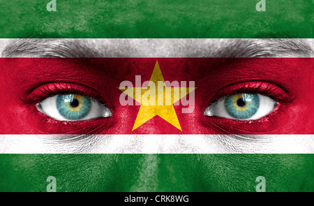 Menschliches Gesicht gemalt mit Flagge von Suriname Stockfoto