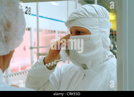 Mitarbeiter im Reinraum am Telefon mit Kollegen Stockfoto