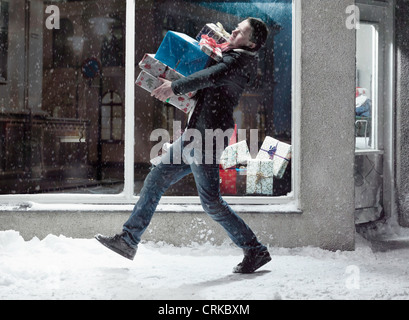 Mann trägt Weihnachtsgeschenke im Schnee Stockfoto