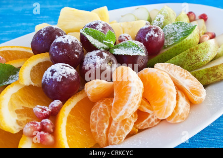 Bunte Früchte in Puderzucker auf blauem Hintergrund Stockfoto