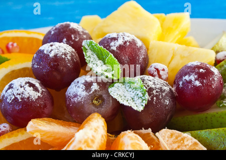 Bunte Früchte in Puderzucker auf blauem Hintergrund Stockfoto