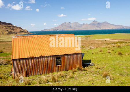 Eine alte Wellblech-Scheune am Cleadale auf der Insel Eigg, mit Blick auf die Isle of Rum, Schottland, UK. Stockfoto