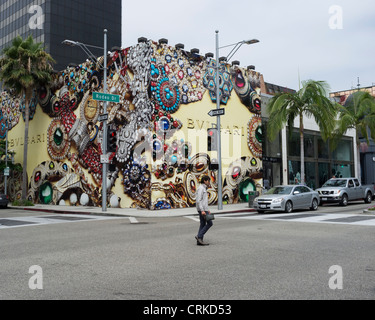 Ein einsamer Mann kreuzt Rodeo Drive, Beverly Hills vor einem großen Bvlgari Shop und Kunstwerk Stockfoto