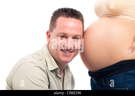 Glücklich lächelnd werdender Vater hören schwangeren Bauch, isoliert auf weißem Hintergrund. Stockfoto