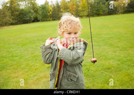 Jungen spielen mit Kastanien an Schnur Stockfoto