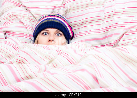 Angst vor Frau Winter Hut versteckt in Bettdecke gewickelt. Stockfoto