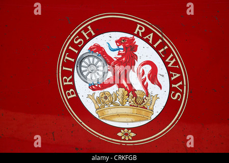 Das Logo der British Railways auf der Seite des roten Wagens ist mit schmutzigen Markierungen bespritzt - Nahaufnahme des Löwenwappens auf der BR-Lokomotive Stockfoto