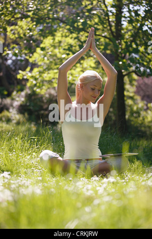 Eine junge Frau, die mit Blick auf eine digital-Tablette während Yoga außerhalb üben Stockfoto