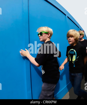 London, England. Zwei jungen vorbei an temporären Wand - stark digital manipuliert Stockfoto
