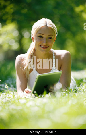 Eine junge Frau im Gras mit einem digital-Tablette Stockfoto