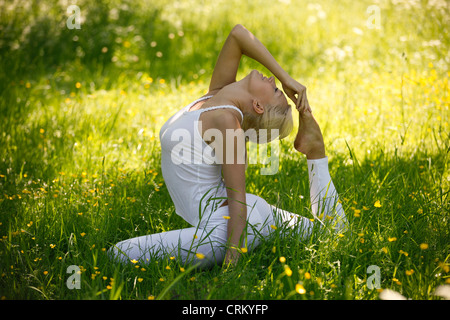 Eine junge Frau praktizieren Yoga außerhalb, stellen Taube Stockfoto