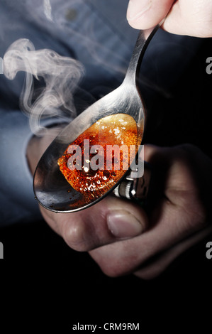 Man kocht Drogen auf einem Löffel mit einem Feuerzeug Stockfoto