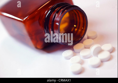 Eine verschüttete rote Flasche weißen Tabletten auf einem Tisch. Stockfoto