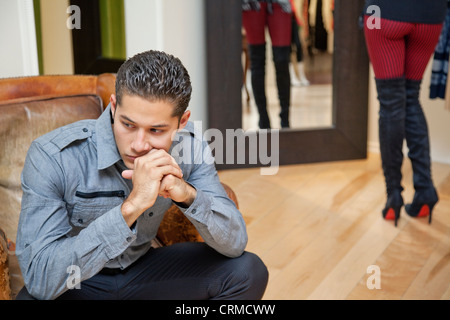 Nachdenklichen jungen Mann, sitzend mit Freundin im Hintergrund Stockfoto