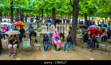 paris, Frankreich, französisches Publikum, im Regen mit Regenschirmen, die das nationale Musikfestival, das „Fete de la Musique“, das klassische Musikkonzert in den Jardin de Luxembourg, den Frühling, das Musikfestival Sitzen, den Jardin de Luxembourg hören Stockfoto