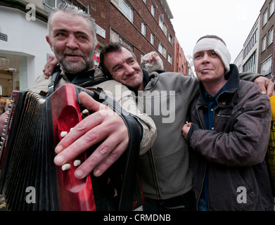 Gruppe von drei Obdachlose Männer One verletzt spielt Akkordeon in der Straße Stockfoto