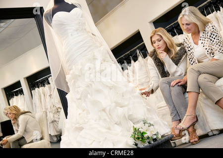 Mutter und Tochter beim betrachten elegantes Brautkleid im Brautladen auf Sofa sitzen Stockfoto