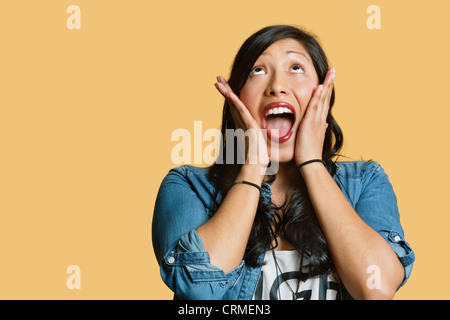 Überrascht, junge Frau mit Kopf in Händen auf farbigem Hintergrund Stockfoto