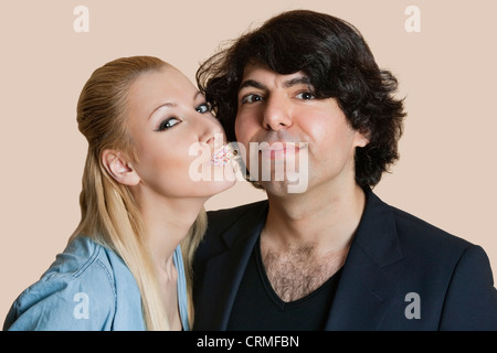 Bildnis einer blonden Frau mit bestreut Lippen küssen jungen Mann über farbigen Hintergrund Stockfoto