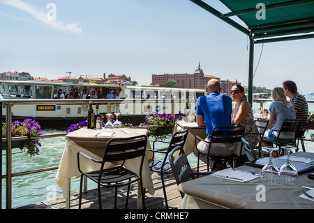 Eine Weitergabe valporetto Diners Essen an einem Kanal Seite Restaurant in Dorsoduro Venedig. Stockfoto