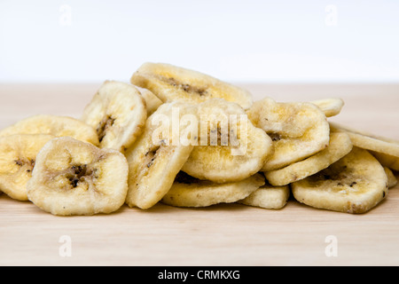 Getrocknete Bananenchips auf Schneidbrett aus Holz auf einem weißen Hintergrund Stockfoto