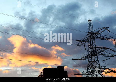 Ein Strommast gegen ein bewölkter Himmel bei Sonnenuntergang Stockfoto