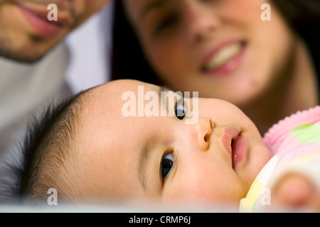 Ein verspieltes kleines Mädchen Nahaufnahme. Vater und Mutter im Hintergrund. Stockfoto