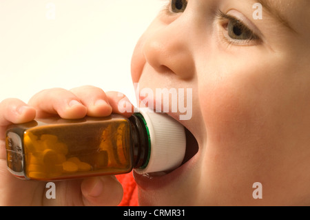 Kleiner Junge er eine versiegelte Medizin-Flasche in den Mund Stockfoto