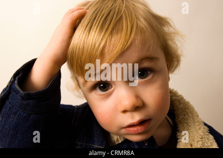 Ein kleiner Junge, kratzte sich am Kopf. Stockfoto