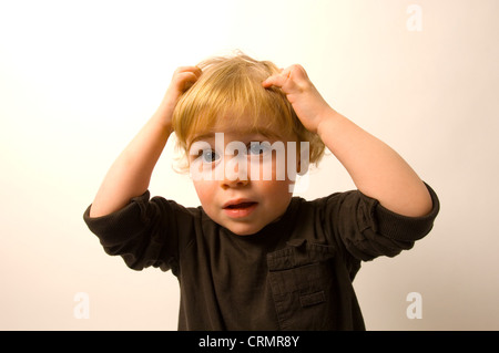 Ein kleiner Junge, kratzte sich am Kopf. Stockfoto