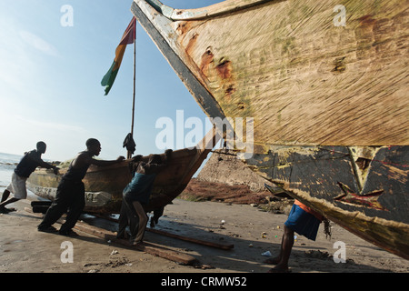 Fischer ziehen ihr Boot am Strand von Cape Coast, Ghana Stockfoto