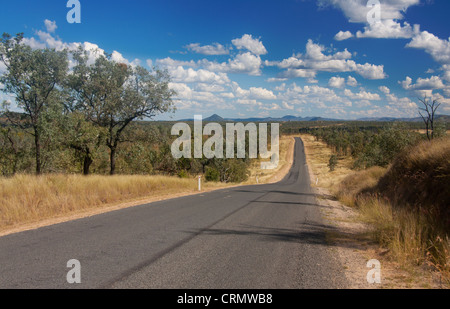 Outback / Busch Landstraße in der Nähe von Clermont bergab mit flachen Landschaft und Berge in der Ferne in der Nähe von Clermont Qld Australien Stockfoto