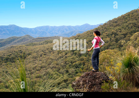 Einzigen weiblichen Wanderer blickt auf den Blick in Bergen mit Wald unter ihr Stockfoto