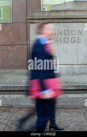 Ein Mann und eine Frau zu Fuß vorbei an einem Steinsockel mit London Bridge in sie geschnitzt. Stockfoto