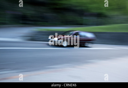 Geschwindigkeitsüberschreitung-Konzept - Bewegung verwischt Auto schnell auf eine kleine Straße den Berg hinauf gehen Stockfoto
